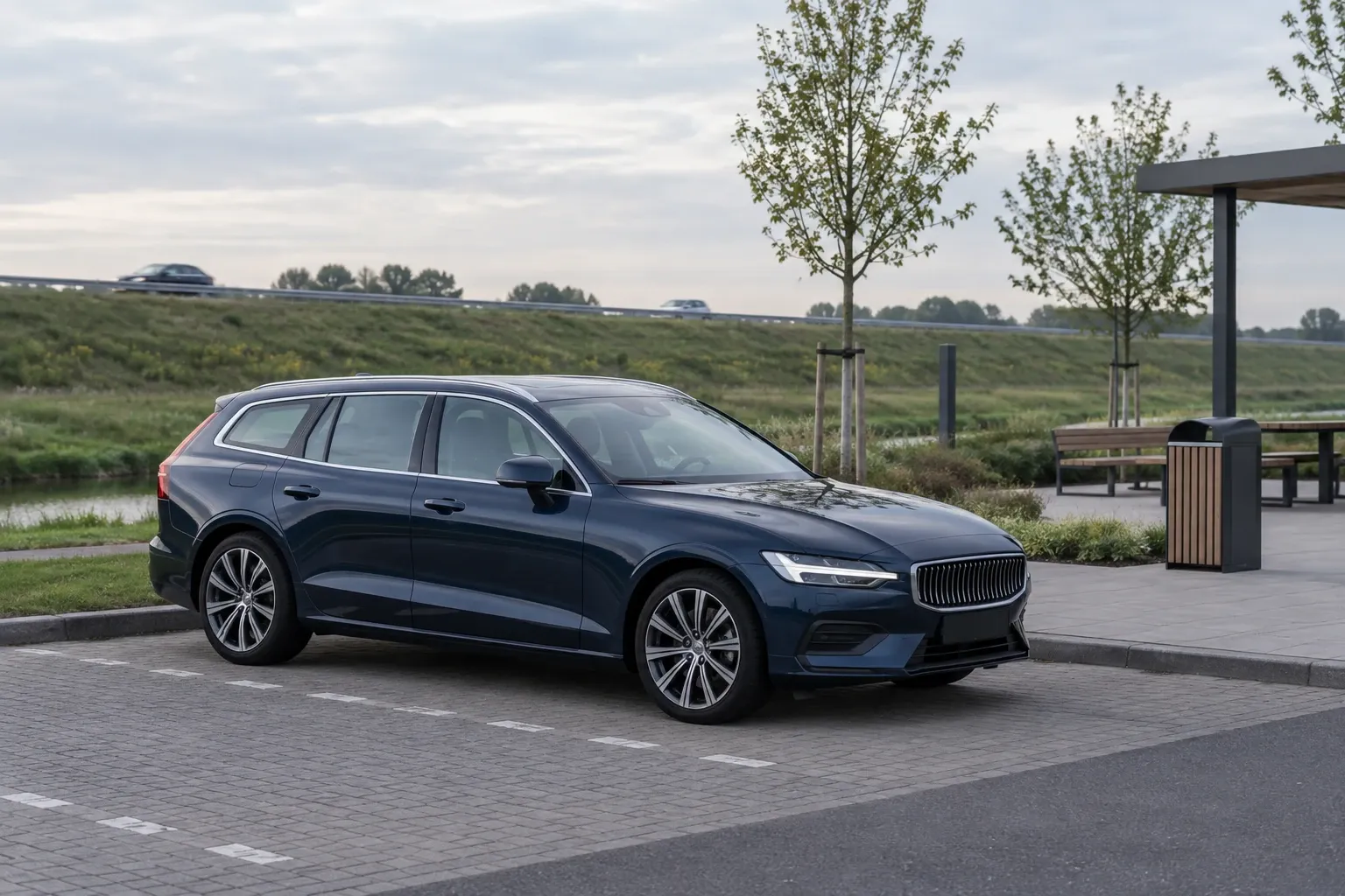 Donkere stationwagen geparkeerd bij verzorgingsplaats naast een snelweg, avondlicht
